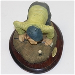 'History of Golf' Figure with Golfer Trying to Blow Ball in Hole